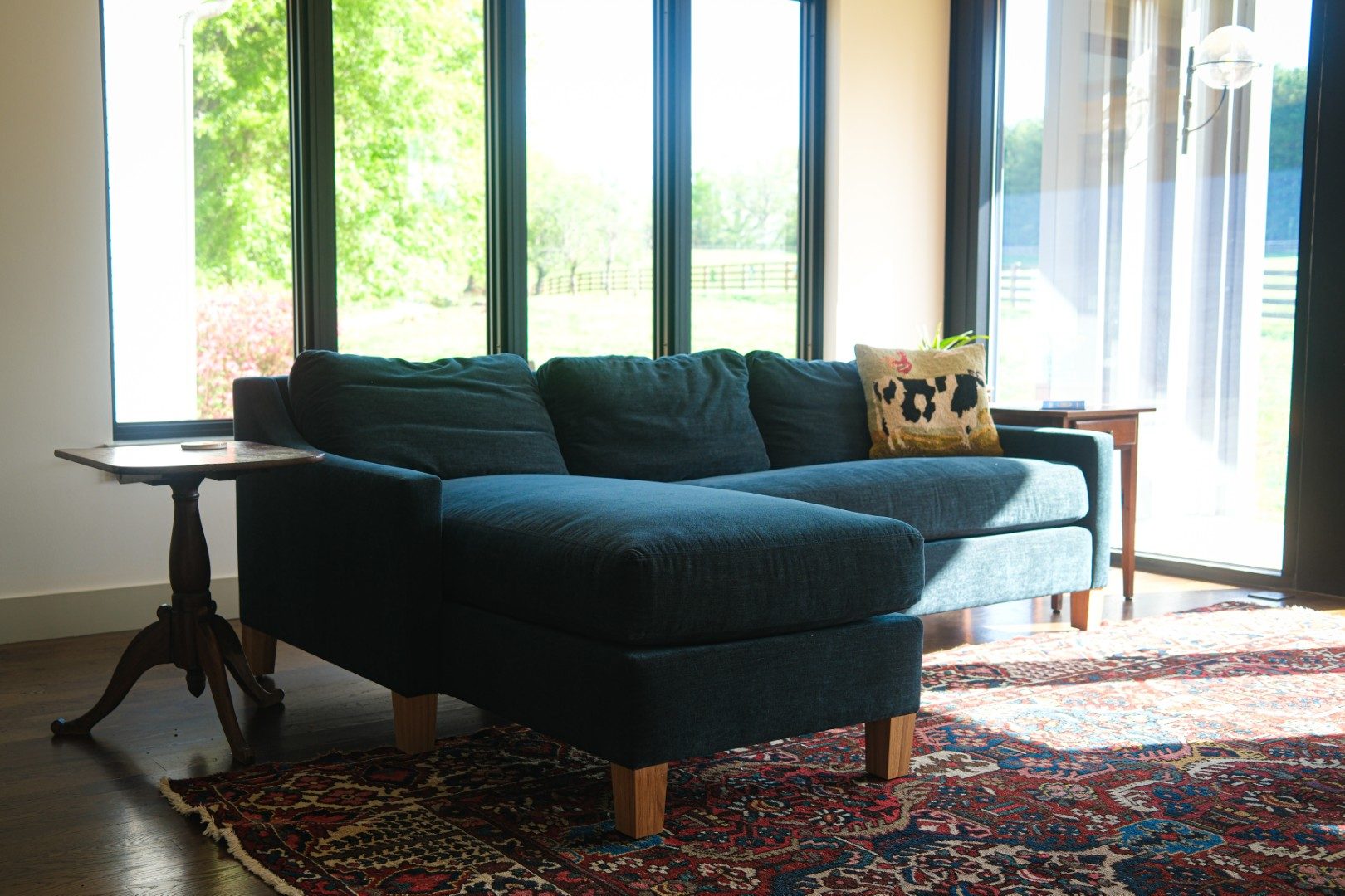 Deep teal chaise sectional by floor-to-ceiling windows