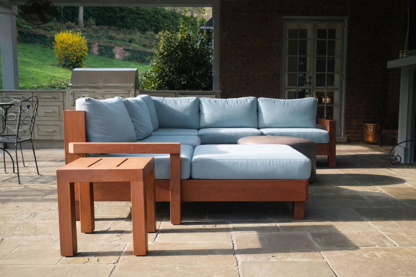 Blue-cushion outdoor sectional with a wood frame on a stone patio