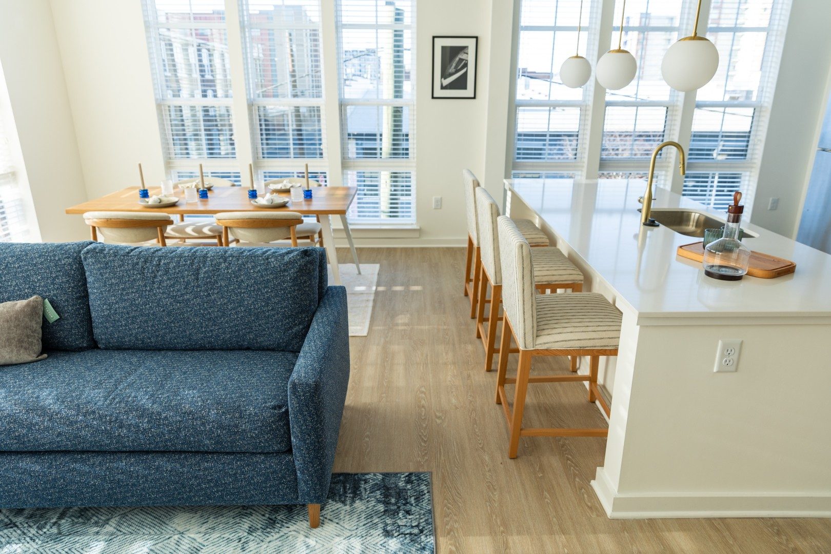 Blue sofa, striped counter stools and dining area in a bright open room
