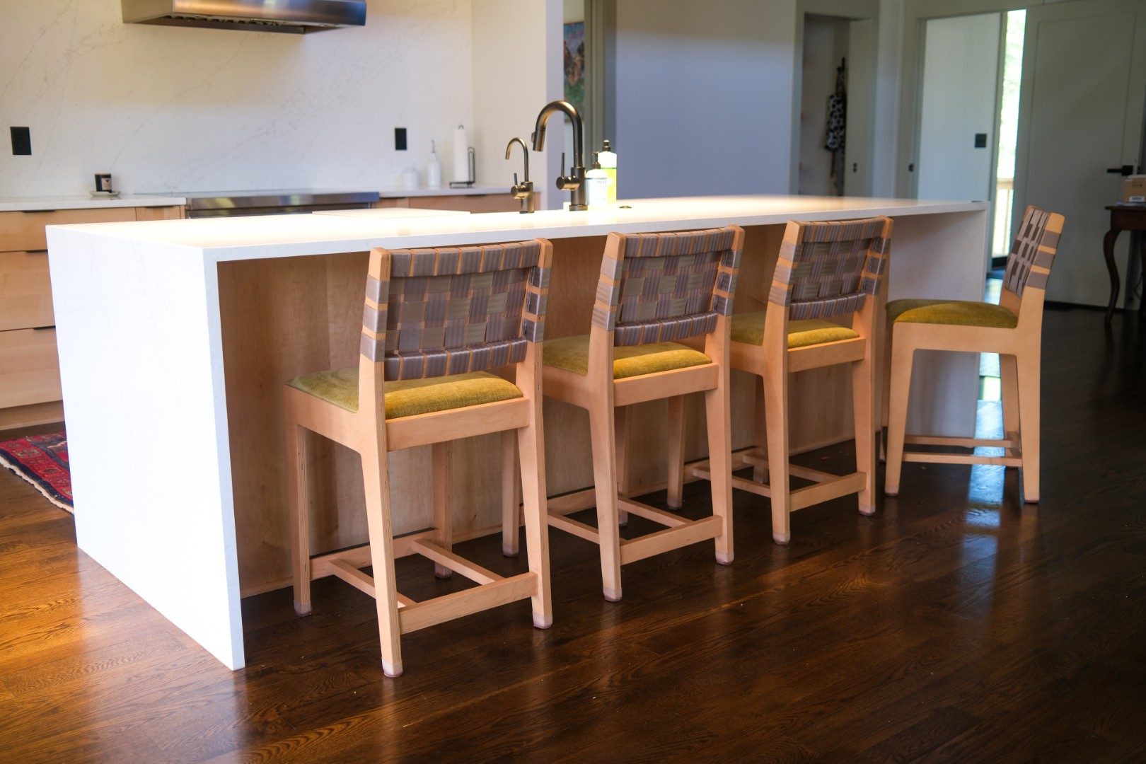 Wood counter stools with woven backs at a waterfall island