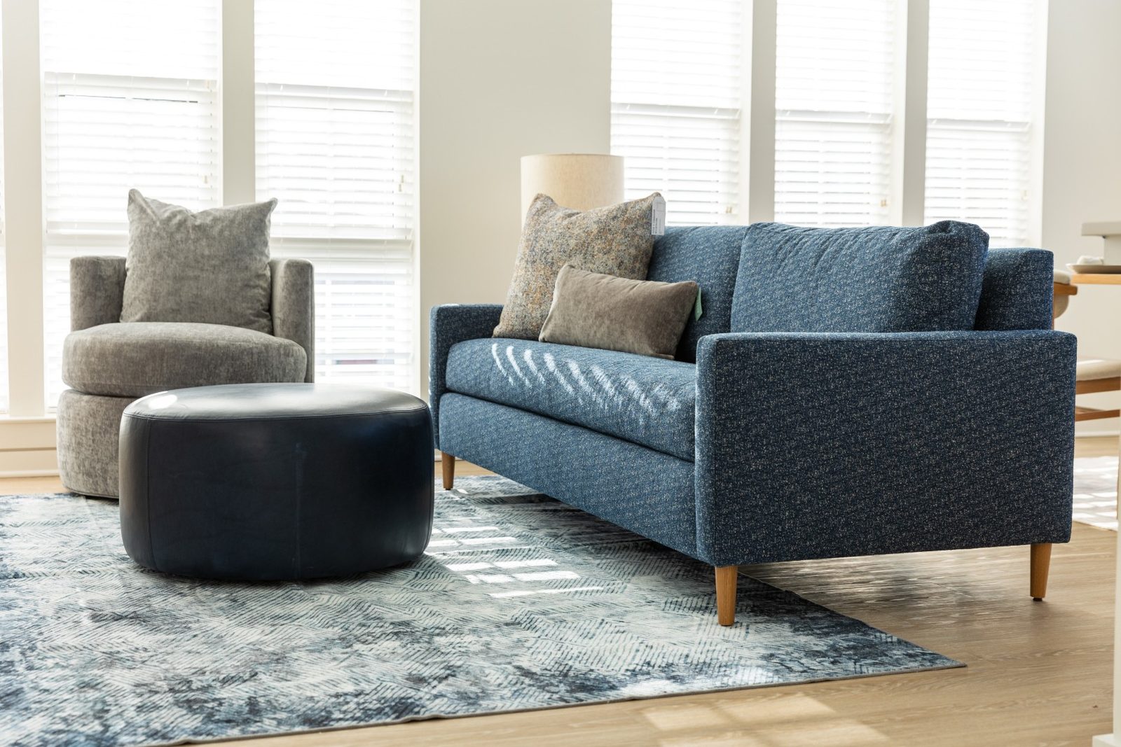 Black velvet mid-century sofa with tufted back cushions and walnut legs on a woven rug
