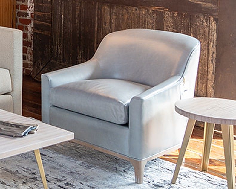 Light blue-gray leather lounge chair with a curved back and wood base