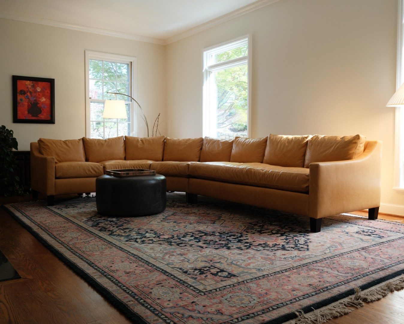 Tan leather curved sectional on a patterned rug