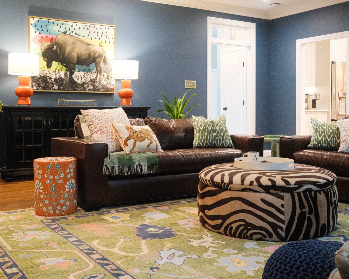 Brown leather sofa and zebra-print ottoman against a deep blue wall