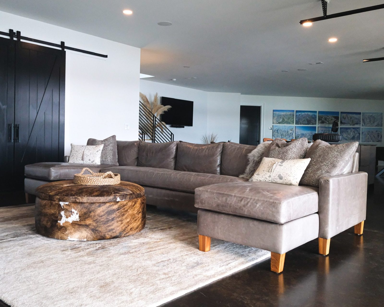 Gray leather sectional with a cowhide ottoman on a cream rug